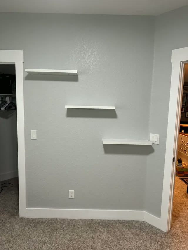 Three floating shelves installed on a bedroom wall