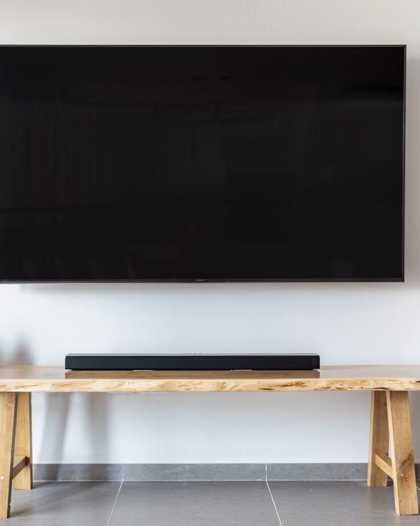 A flat-screen TV mounted on a wall above a wooden console, no cables in sight